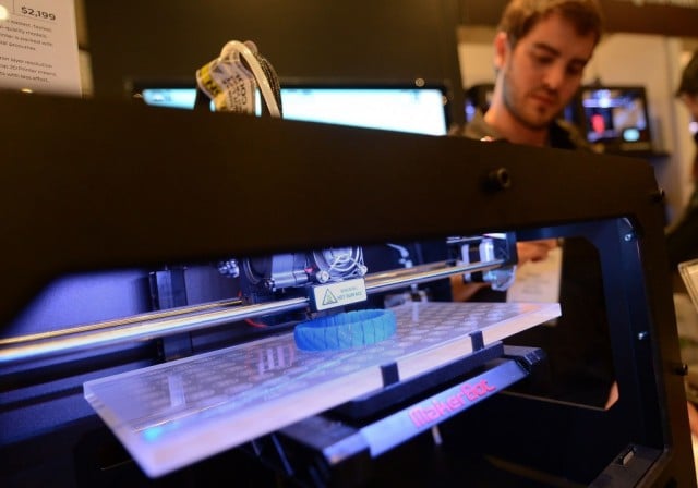 Visitors look at a 3D printer printing an object, during 'Inside 3D Printing' conference and exhibition in New York, April 22, 2013. The exhibition features on April 22-23, 2013, tutorials and seminars offering blueprints on how to invest and utilize 3D printing in coming years, as well as leading manufacturers and developers displaying their latest 3D printers and services. AFP PHOTO/Emmanuel Dunand (Photo by Emmanuel Nunand/AFP/Getty Images)