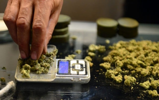A vendor weighs buds for card-carrying medical marijuana patients attending Los Angeles' first-ever cannabis farmer's market at the West Coast Collective medical marijuana dispensary, on July 4, 2014. (Photo source: Frederic J. Brown/AFP/Getty Images)