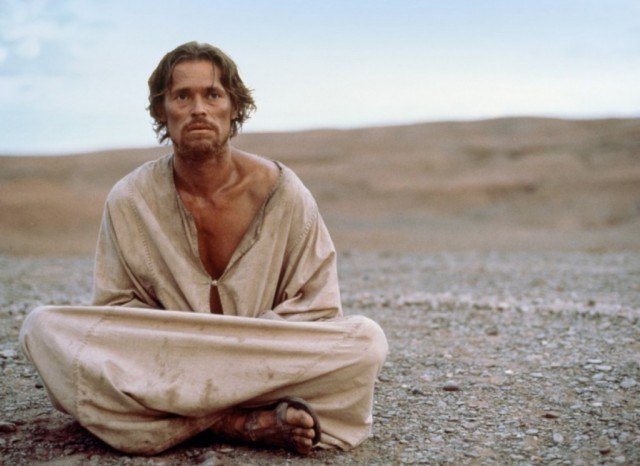 Willem Dafoe as Jesus sitting on the ground wearing sandals and a cloth robe in the desert in The Last Temptation of Christ