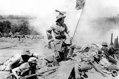 A soldier on the battlefield next to other soldiers and the confederate flag in black and white in The Birth of a Nation
