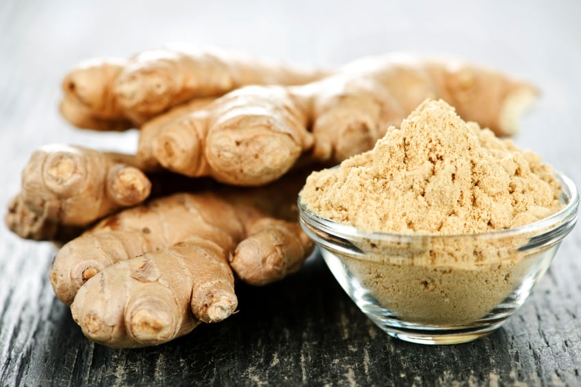 fresh ginger root piled behind a small bowl of dried, ground ginger