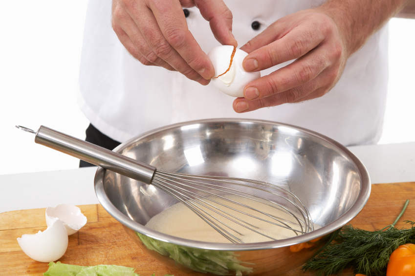 person cracking egg into bowl