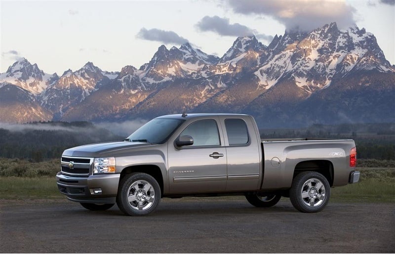 A 2011 Chevy Silverado sits parked in front of picturesque mountains