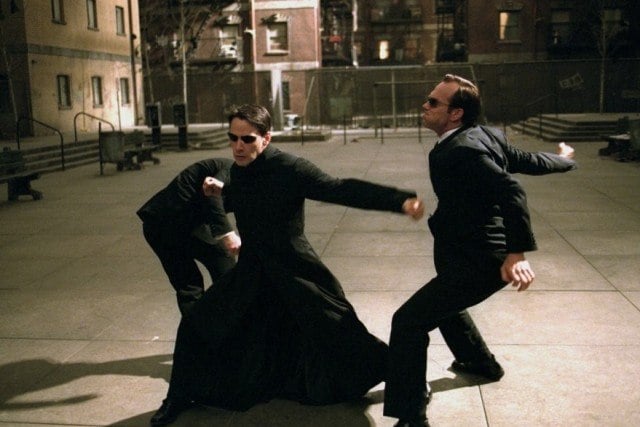 Keanu Reeves' Neo fights two men in suits in a scene from The Matrix Reloaded