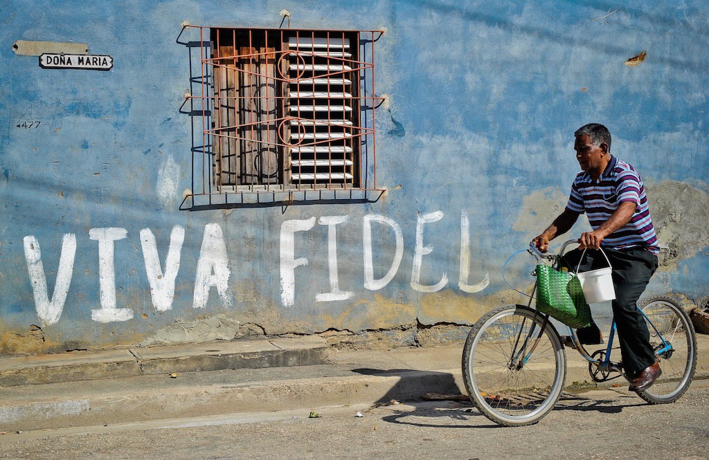 A Cuban rides his bicycle by a graffiti hailing Cuban former president Fidel Castro, on August 12, 2014 in Havana. (Photo by Yamil Lage/AFP/Getty Images)
