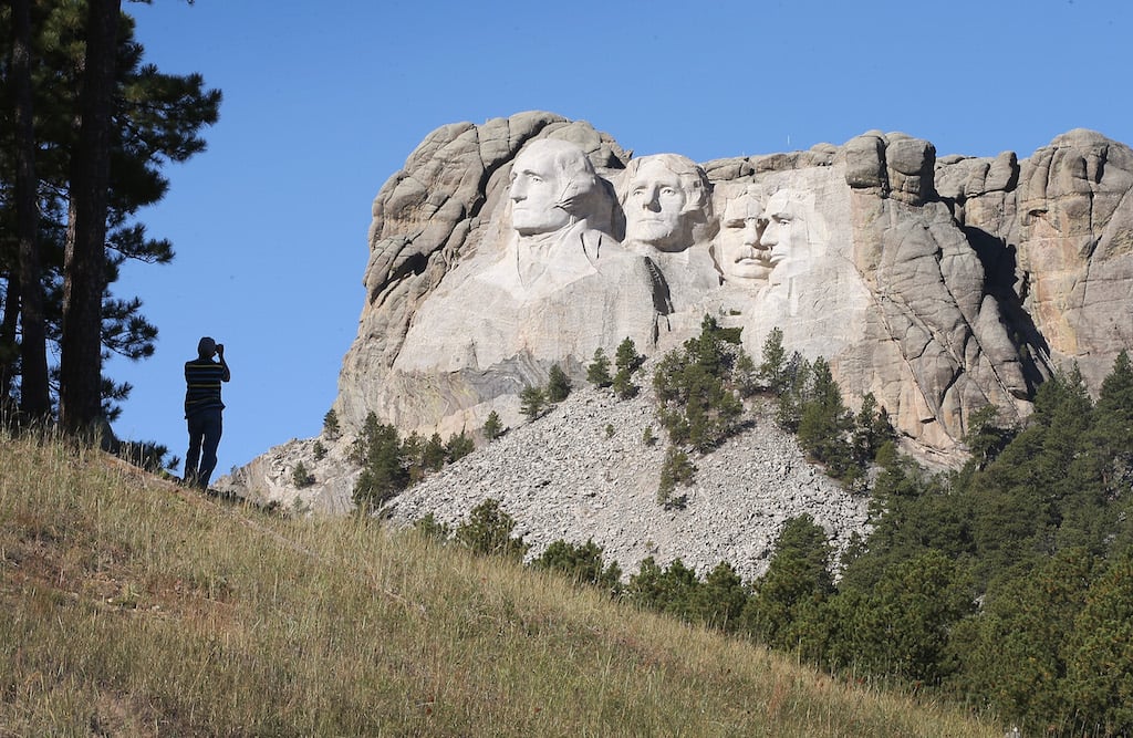 A tourist takes a picture of Mount Rushmore National Memorial 