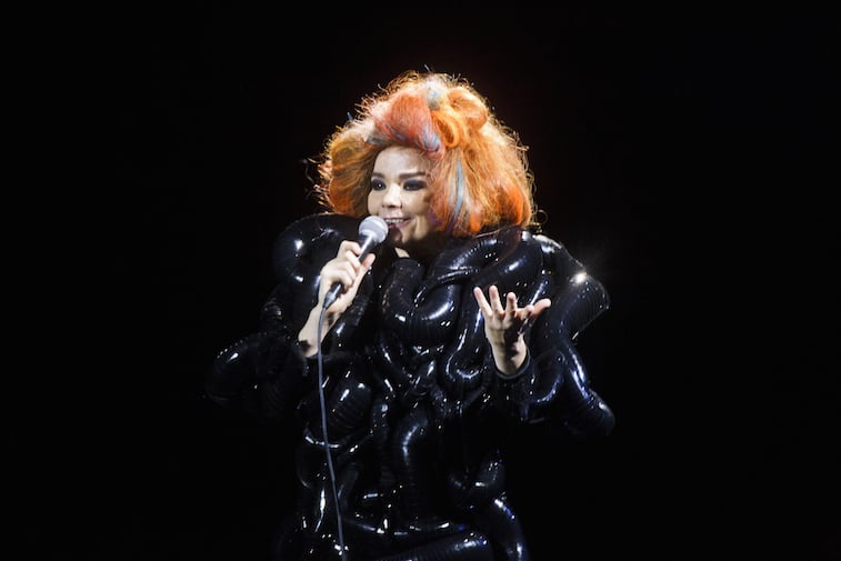 Bjork is on stage in a big black dress and an orange wig.