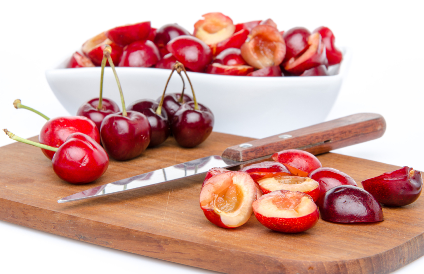 pitting and halving cherries on a cutting board