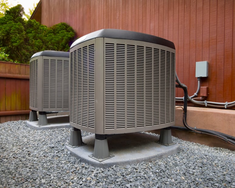 This picture shows an AC heat pump unit outside of a home.