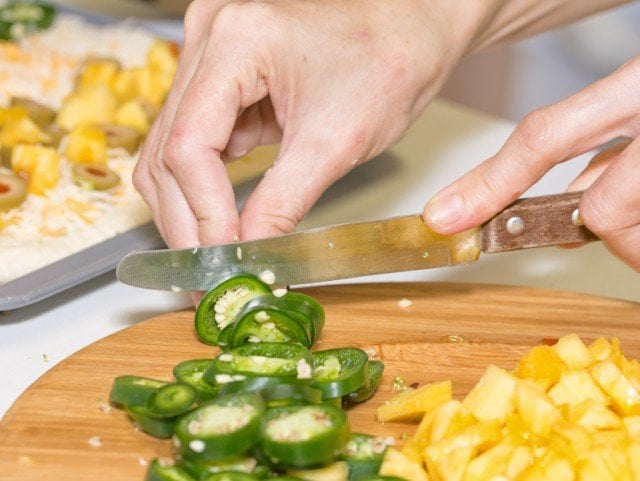 Cutting, chopping, jalapeno, pineapple on wooden board preparing food
