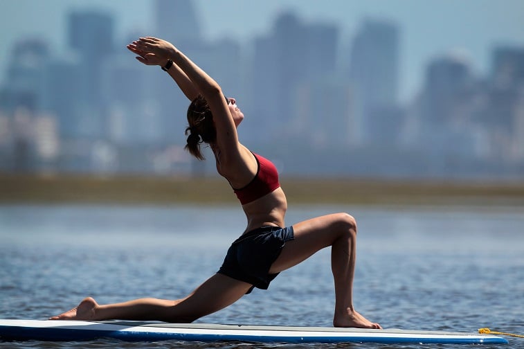 Yoga instructor Sarah Henry leads a class during a paddleboard yoga session - Source: Joe Raedle/Getty Images