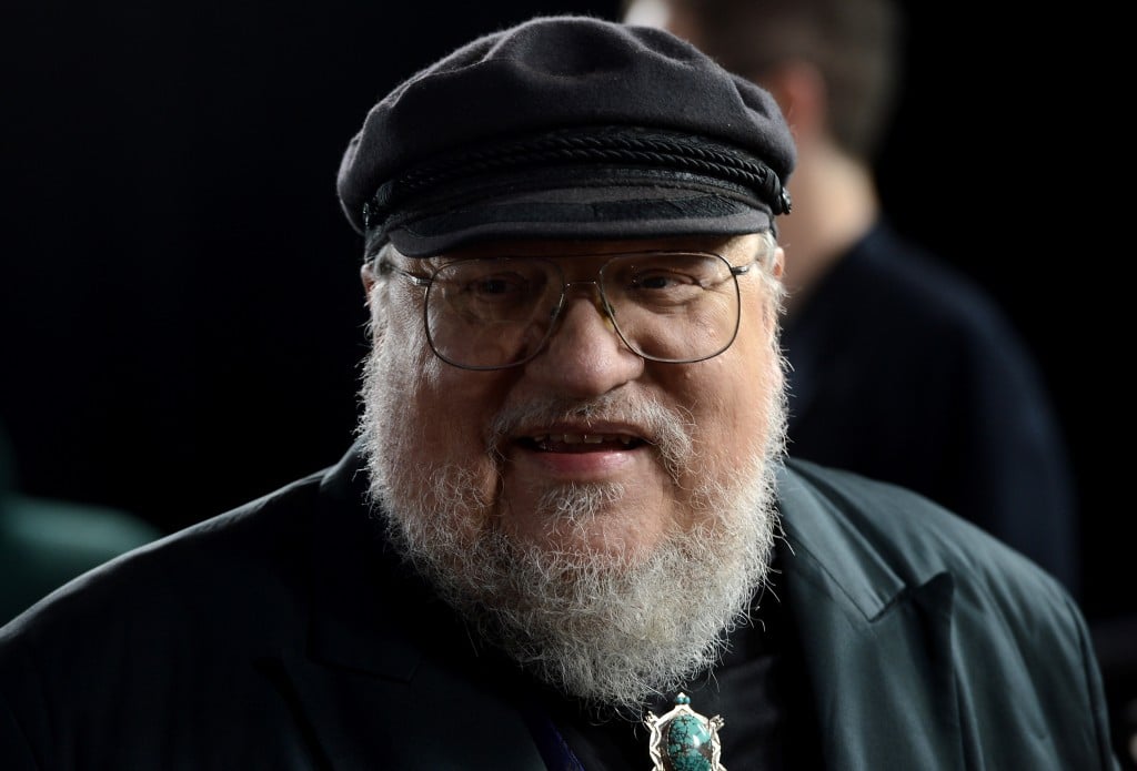 George R.R. Martin wearing a cap and glasses, and smiling