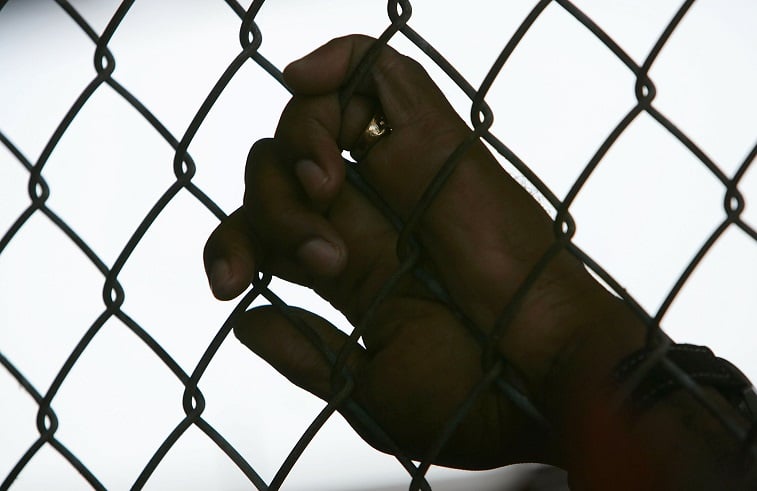 An inmate holds onto a fence - Source: Mario Tama/Getty Images