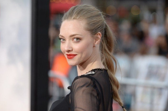 Amanda Seyfriend poses in a black outfit and ponytail on the red carpet.