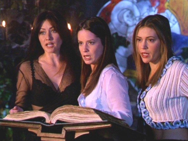Shannon Doherty, Holly Marie Combs and Alyssa Milano look at a large book in Charmed