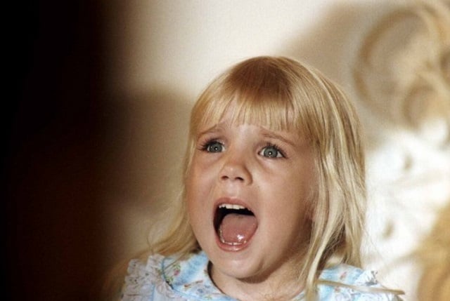 Heather O’Rourke in the movie Poltergeist, looking upward and screaming