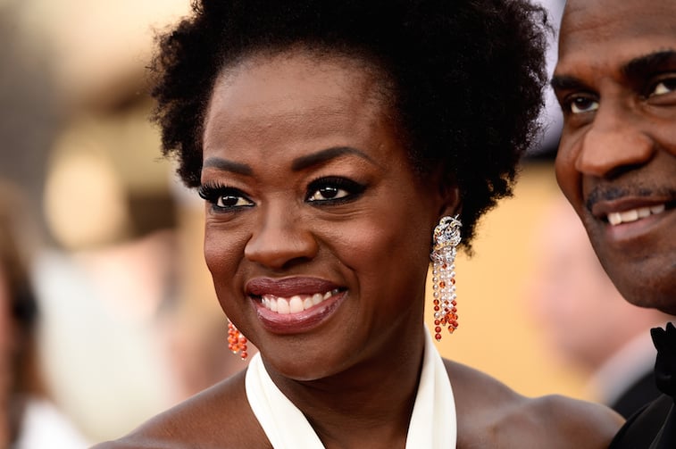 Viola Davis smiling in intricate earrings and a white dress.