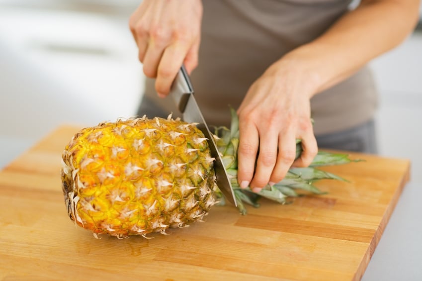close up of someone cutting a pineapple