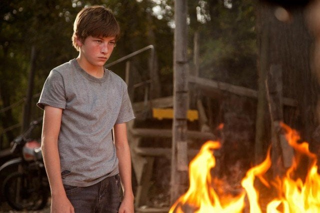 Tye Sheridan stands next to a fire in a scene from Mud