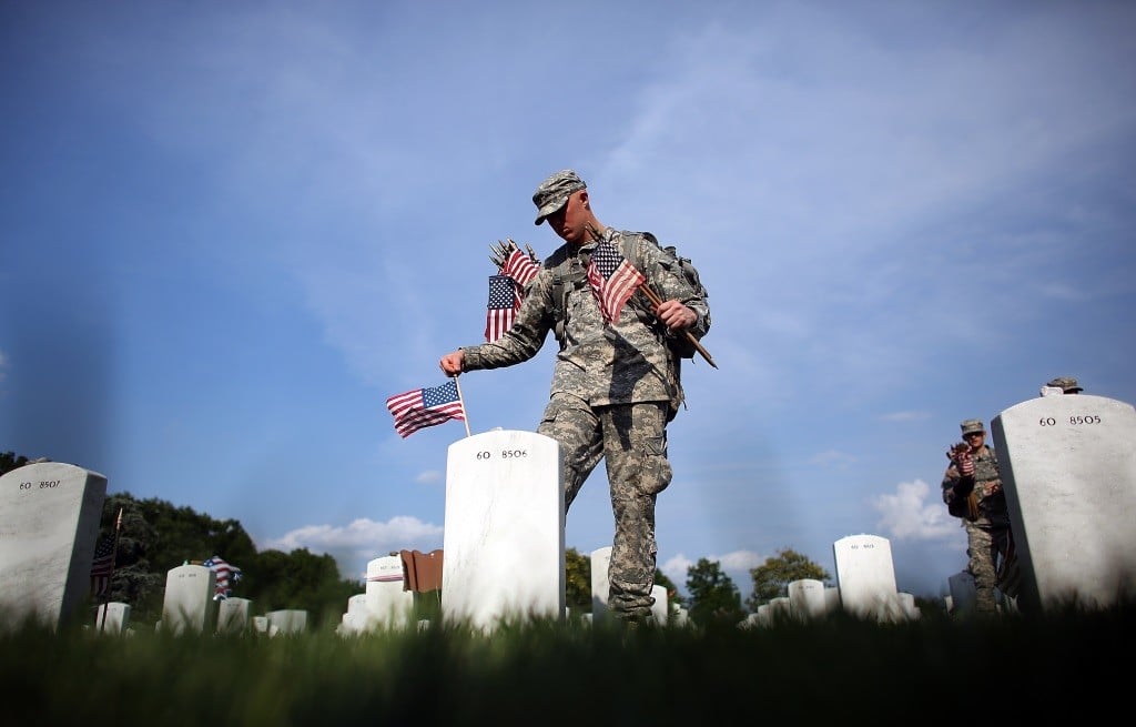 Members of the 3rd U.S. Infantry Regiment place American flags at the graves of U.S. soldiers.