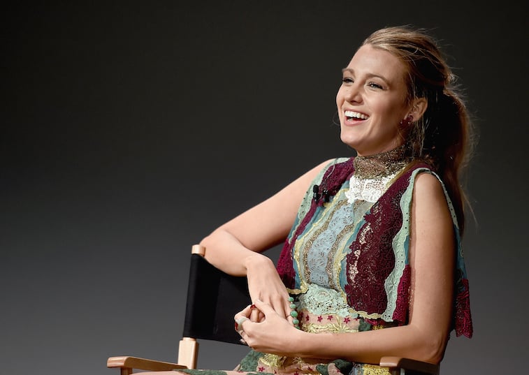 Blake Lively laughing while sitting on a chair on stage. Blake Lively laughing while sitting on a chair on stage.
