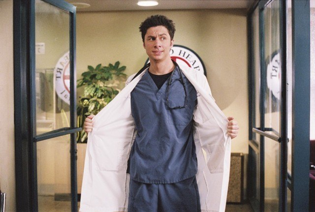 J.D. walking into Sacred Heart Hospital in scrubs and a white jacket, which he is holding open.