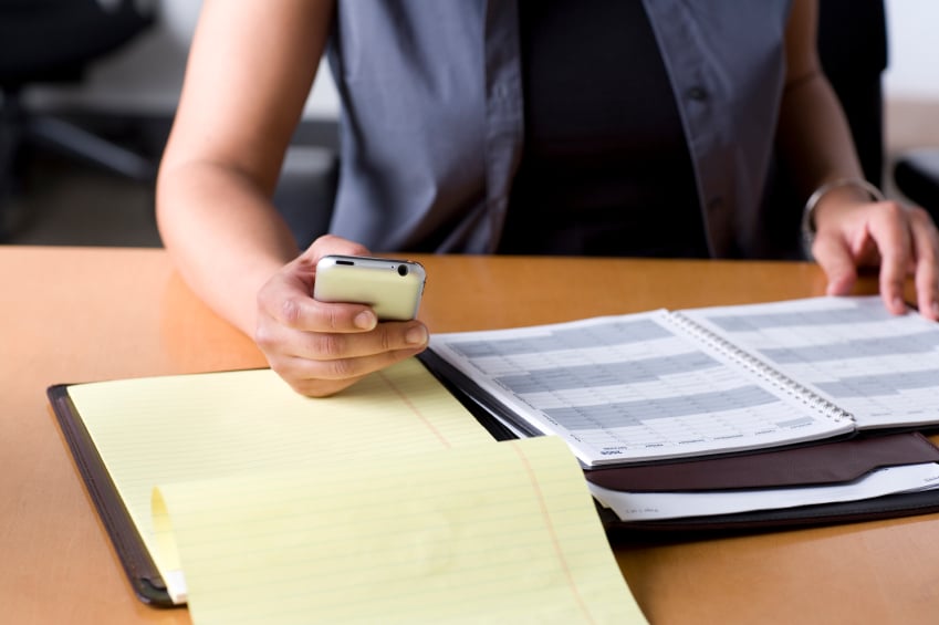 woman checking her phone and creating work distractions