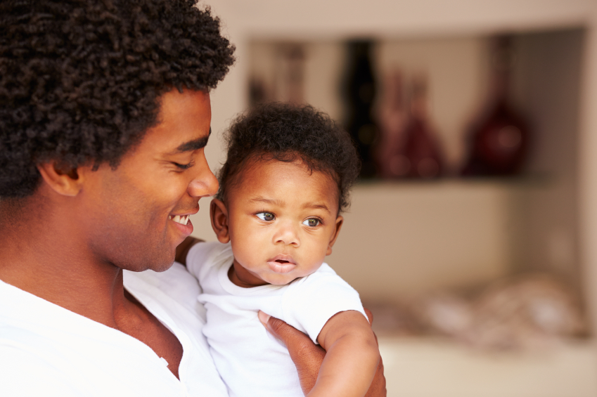 A man smiling while holding his baby