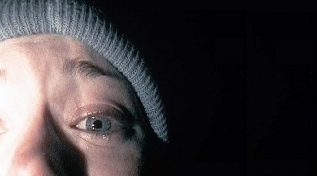 A girl on a video camera, crying and wearing a beanie with her face pressed up against the lens