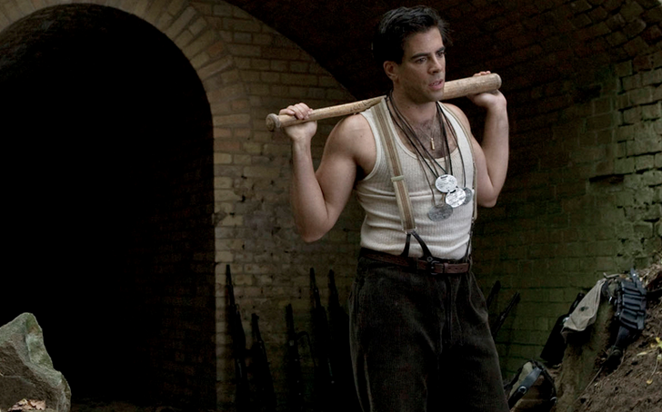 Eli Roth with a bat on his shoulders, wearing a white tank top