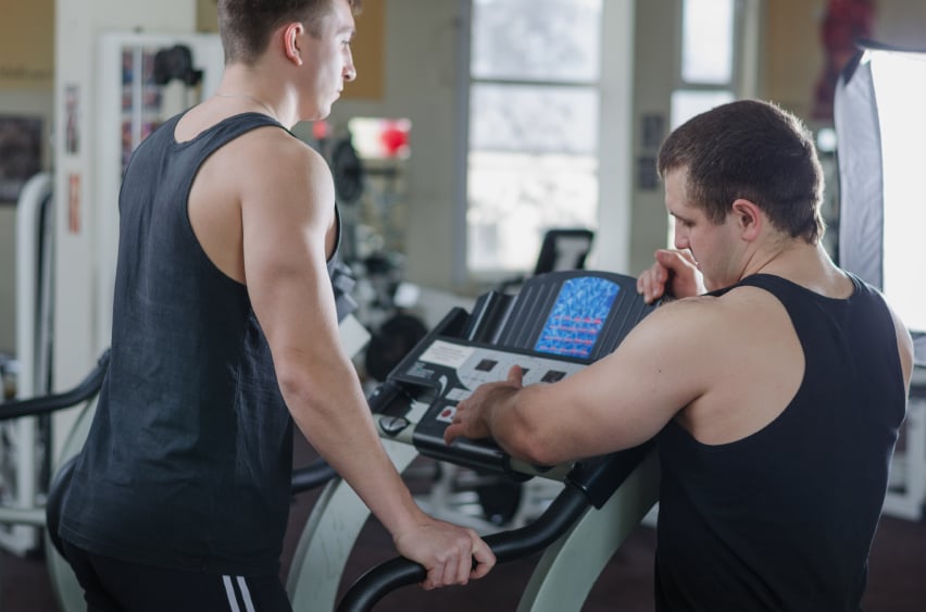 Trainer showing a client how to use the elliptical trainer