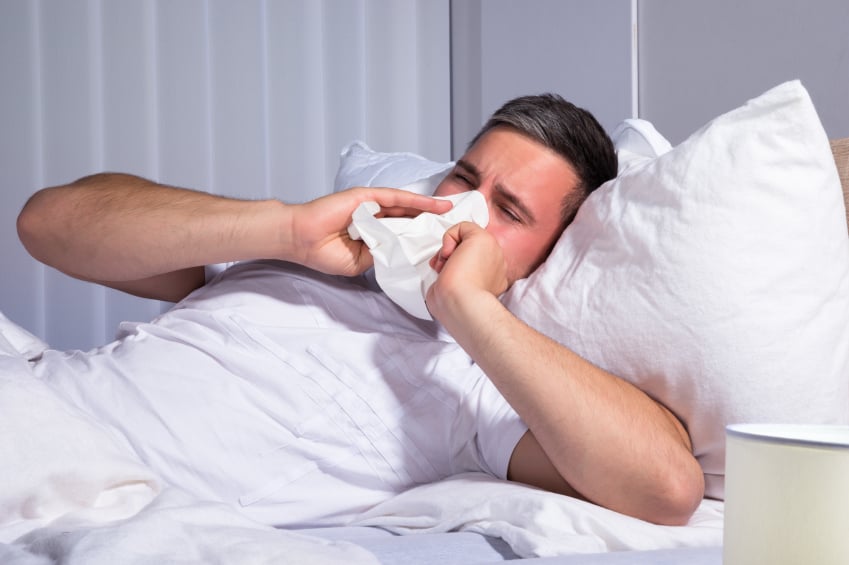 Man suffering from allergies, blowing nose