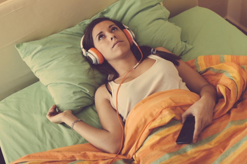 a woman laying in bed listening to music