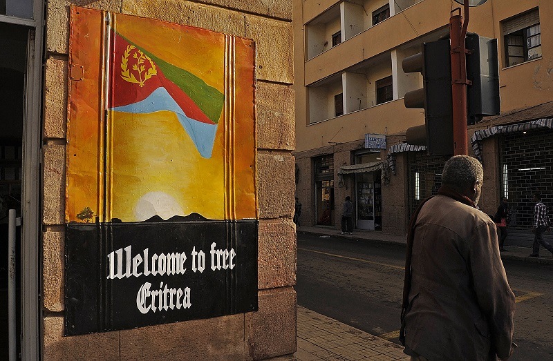 A man waits to cross the road beside a patriotic poster in Asmara, Eritrea
