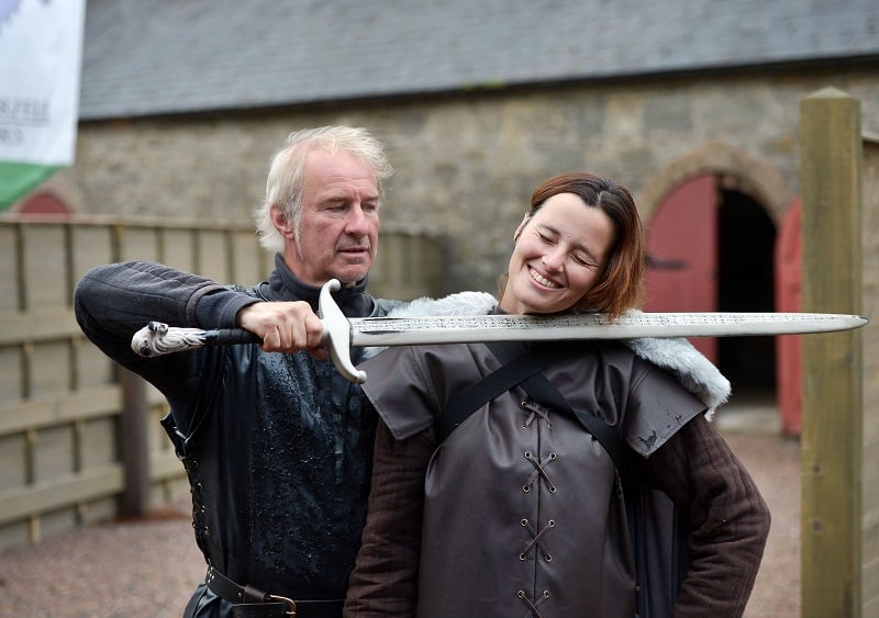 A man holding a sword by a woman