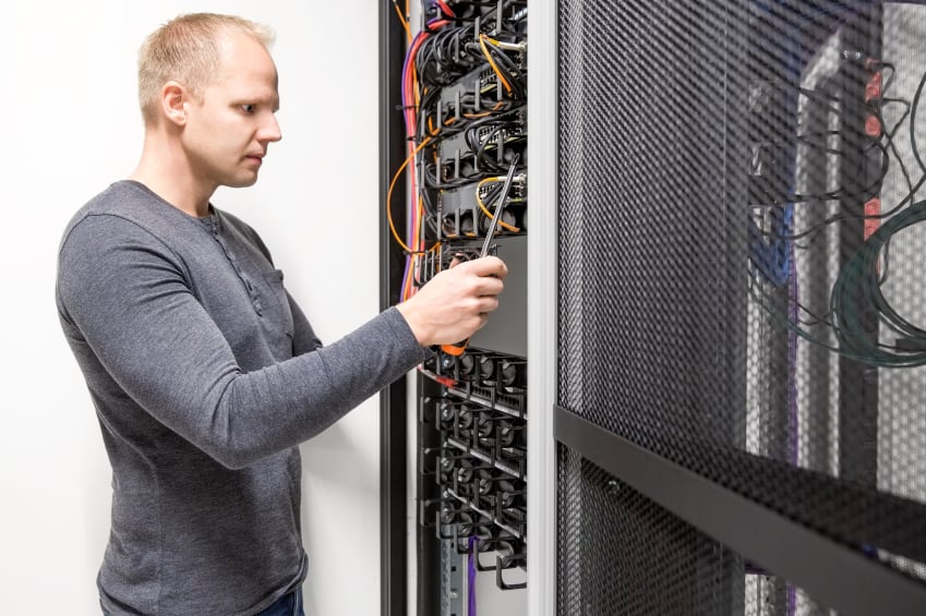 IT engineer or technician builds communication network rack for ethernet and fibre switches in datacenter