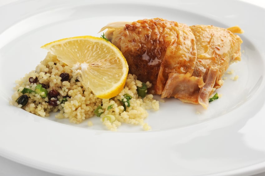 chicken on a plate with a lemon slice and grain