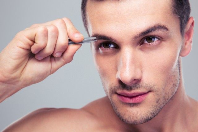 Man removing eyebrow hairs with tweezing, grooming