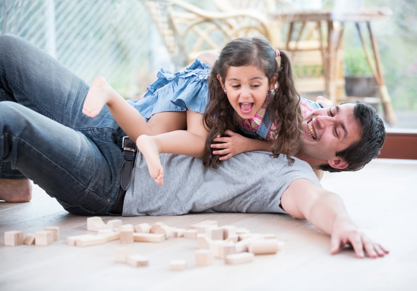 Playful daughters on top of father at home, parents, family
