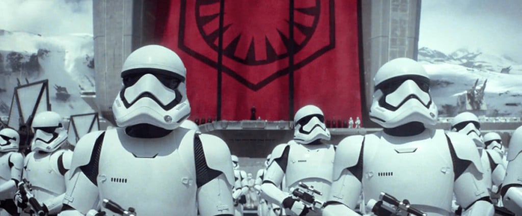 Stormtroopers looking off into the distance, in front of a red banner bearing their logo