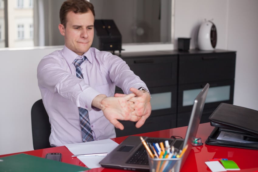 man at desk stretching