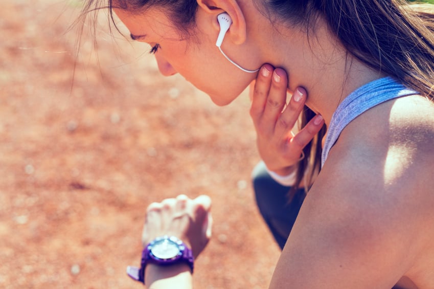 A woman checks her watch while working out