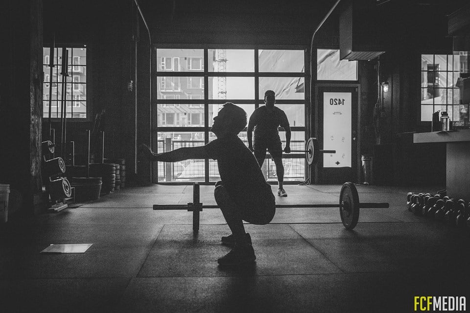 man squatting at a crossfit gym man squatting at a crossfit gym