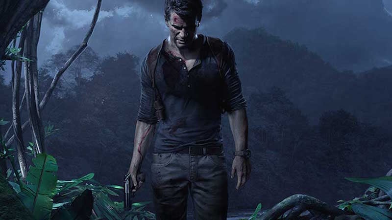 Nathan Drake stands with gun in hand in a jungle.