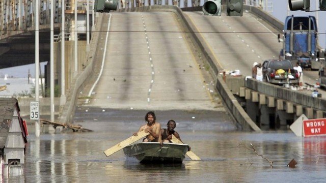 A scene from Spike Lee's documentary 'When the Levees Broke' shows two men paddling a boat away from a bridge in New Orleans