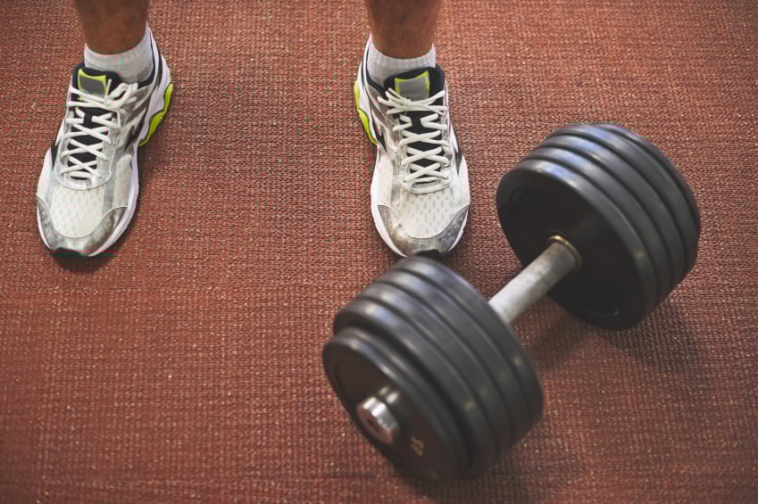 A barbell rests at a man's feet
