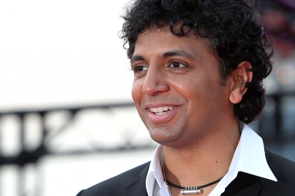 M. Night Shyamalan is smiling on the red carpet.