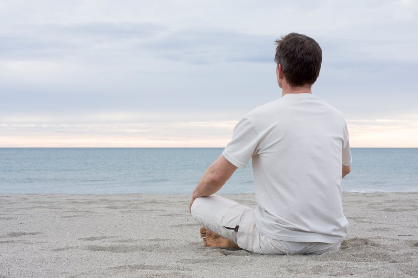 man meditating on beach