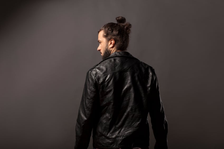 a man with a bun wearing a leather jacket
