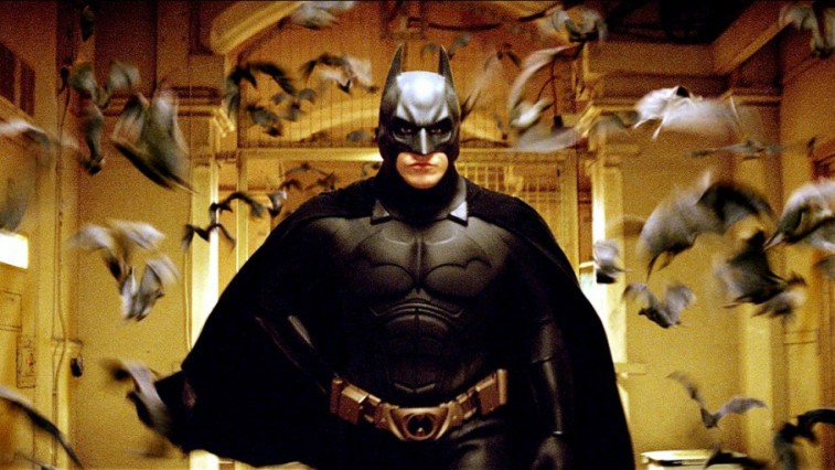 Christian Bale in the Batsuit surrounded by bats in Batman Begins